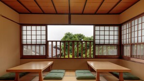 A traditional Japanese room with tatami flooring, wooden tables, and sliding shoji doors. - Gion Ryokan Q-beh - Hostel (Kyoto)