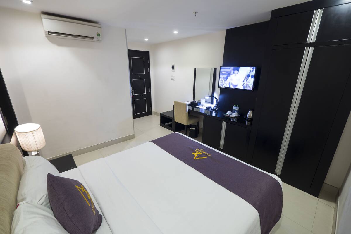 A hotel room with a bed, a desk, a TV, and a wardrobe.