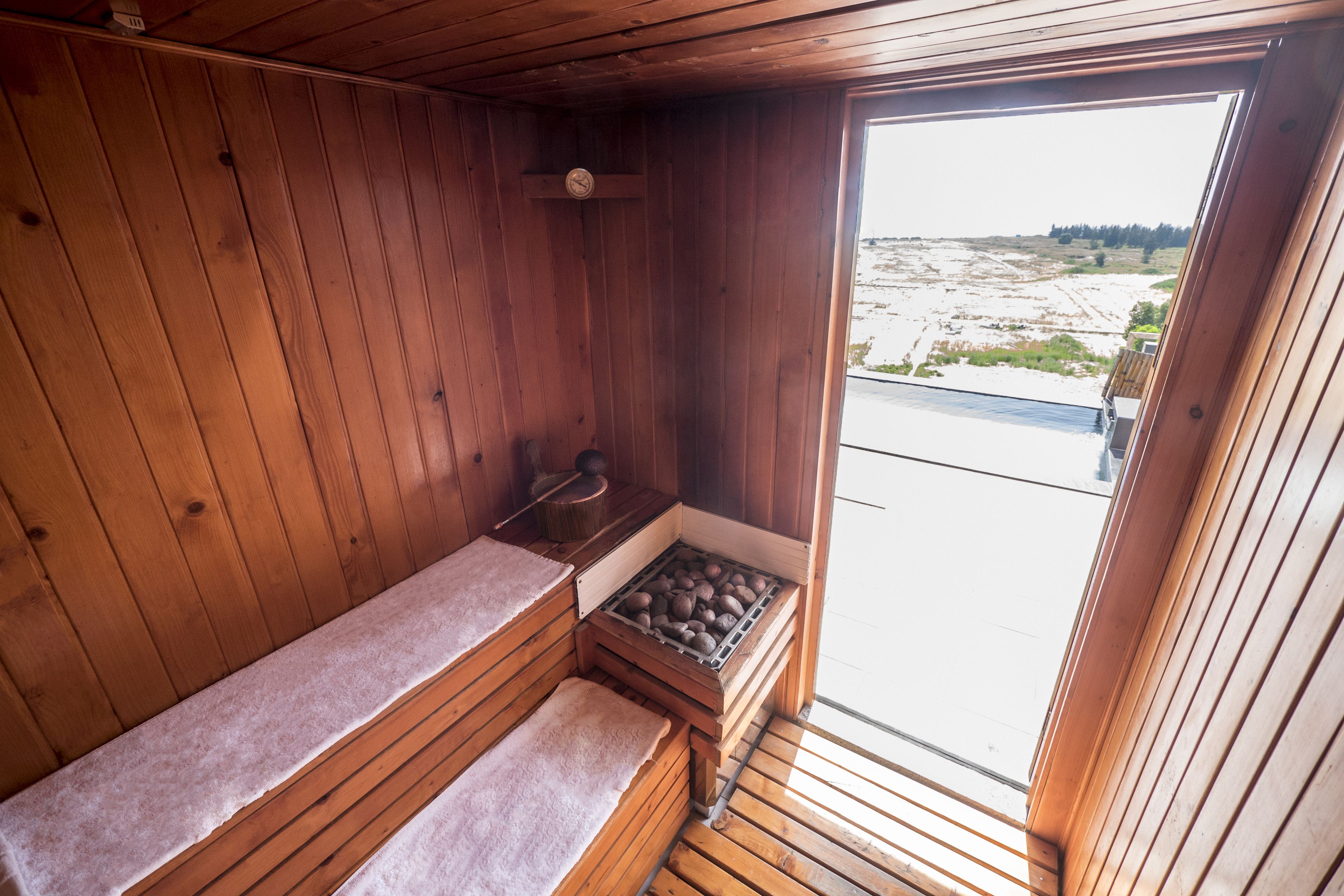 Un sauna con paredes de madera, un banco y una bandeja de piedras.