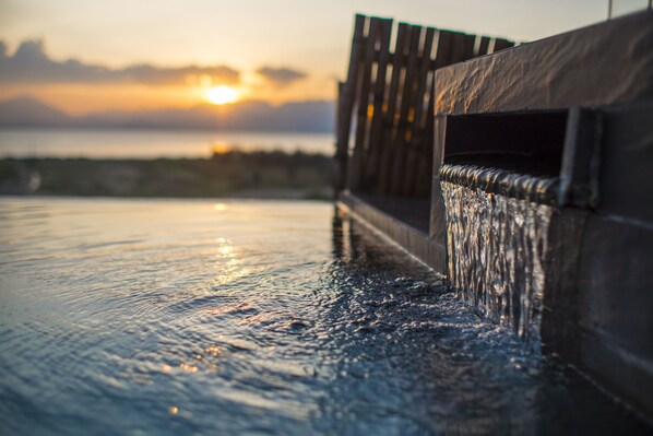 A water feature with a wooden fence and a sunset in the background.