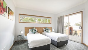 A hotel room with two beds, a small side table, a window with a view of the outdoors, and a sliding glass door leading to an outdoor area. - Nightcap at Federal Hotel Toowoomba (East Toowoomba)