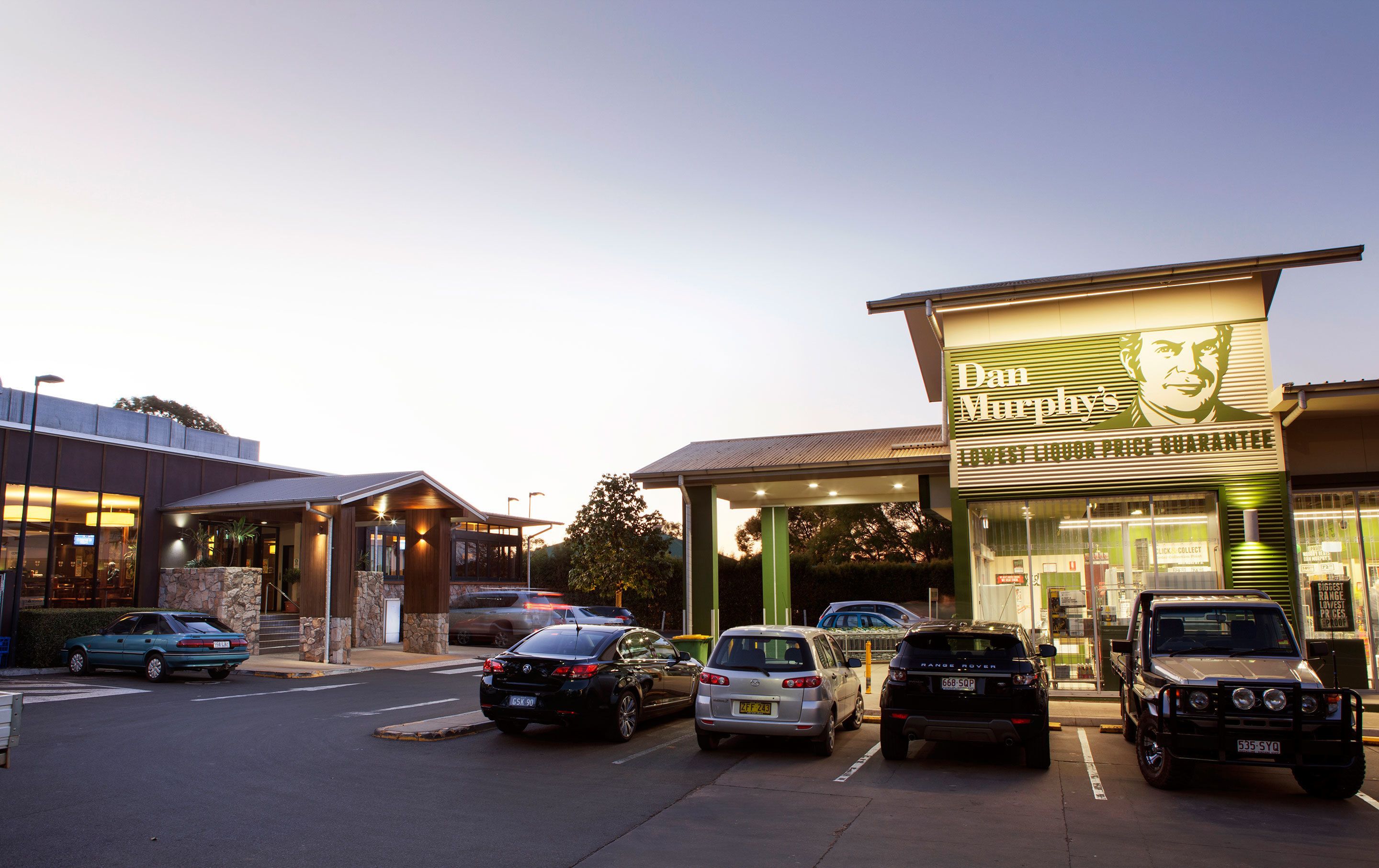 A building with a sign reading "Dan Murphy's" and a parking lot with several cars.