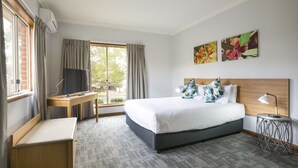A hotel room with a bed, a desk, a TV, a side table, and artwork on the wall. - Nightcap at Federal Hotel Toowoomba (East Toowoomba)