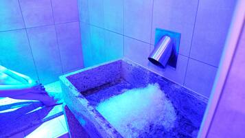 Ein Badezimmer mit einem Becken aus Stein, das mit Eis gefüllt ist, einem an der Wand montierten Fön und einem gefliesten Boden.