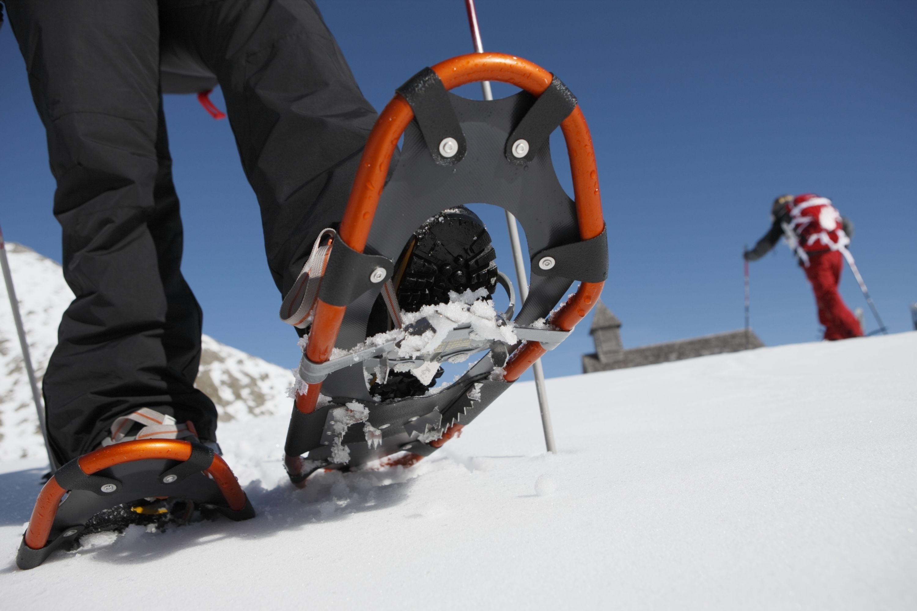A snowshoe with a metal frame and orange handles.