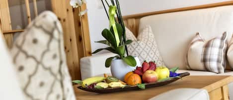 Una mesa de madera con una bandeja de frutas y una orquídea en maceta.