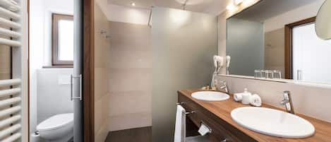 Un baño moderno con dos lavamanos, un espejo grande y una ducha.