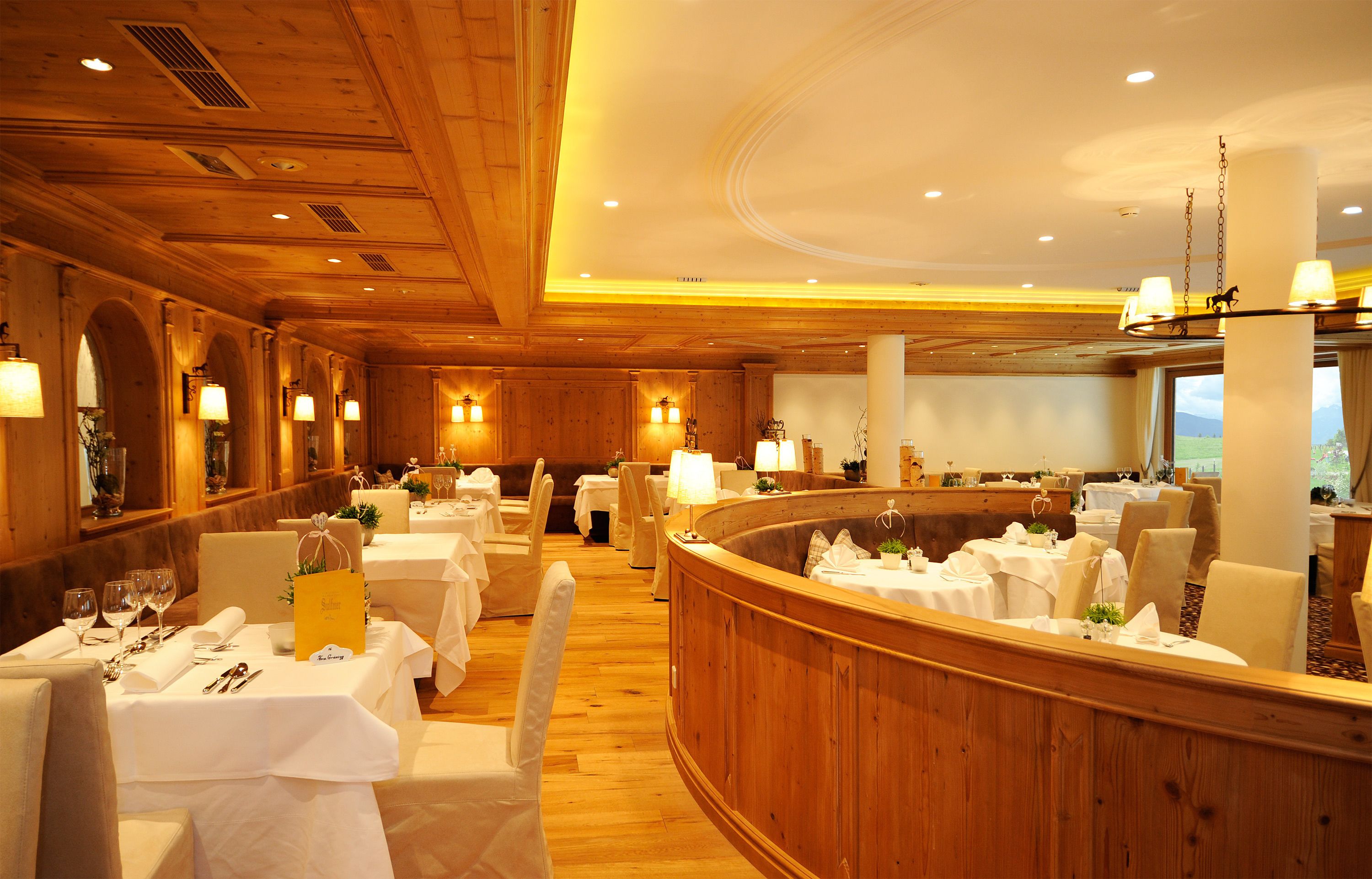 Un restaurante con mesas redondas, manteles blancos y paneles de madera.