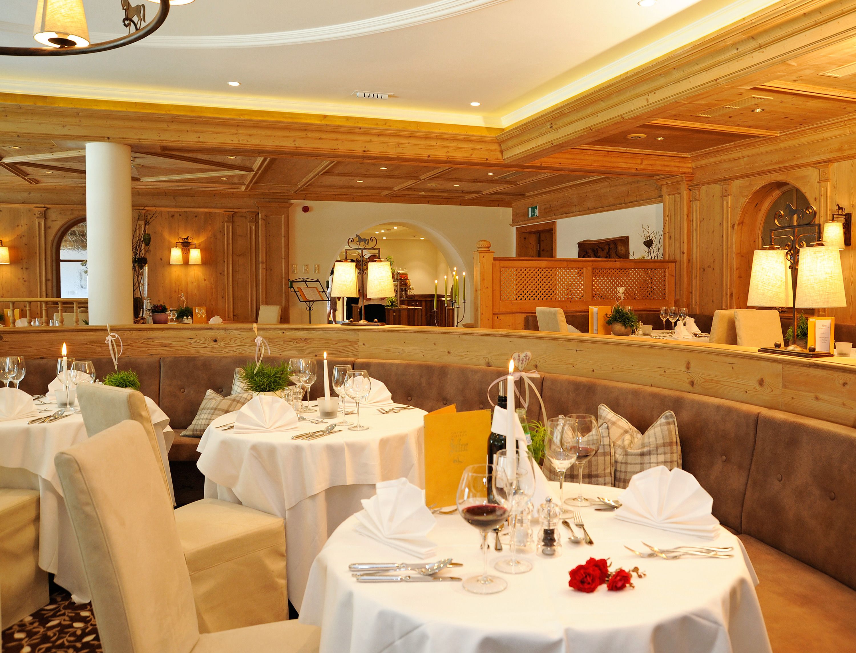 A restaurant with round tables set for dining, featuring white tablecloths and wine glasses.