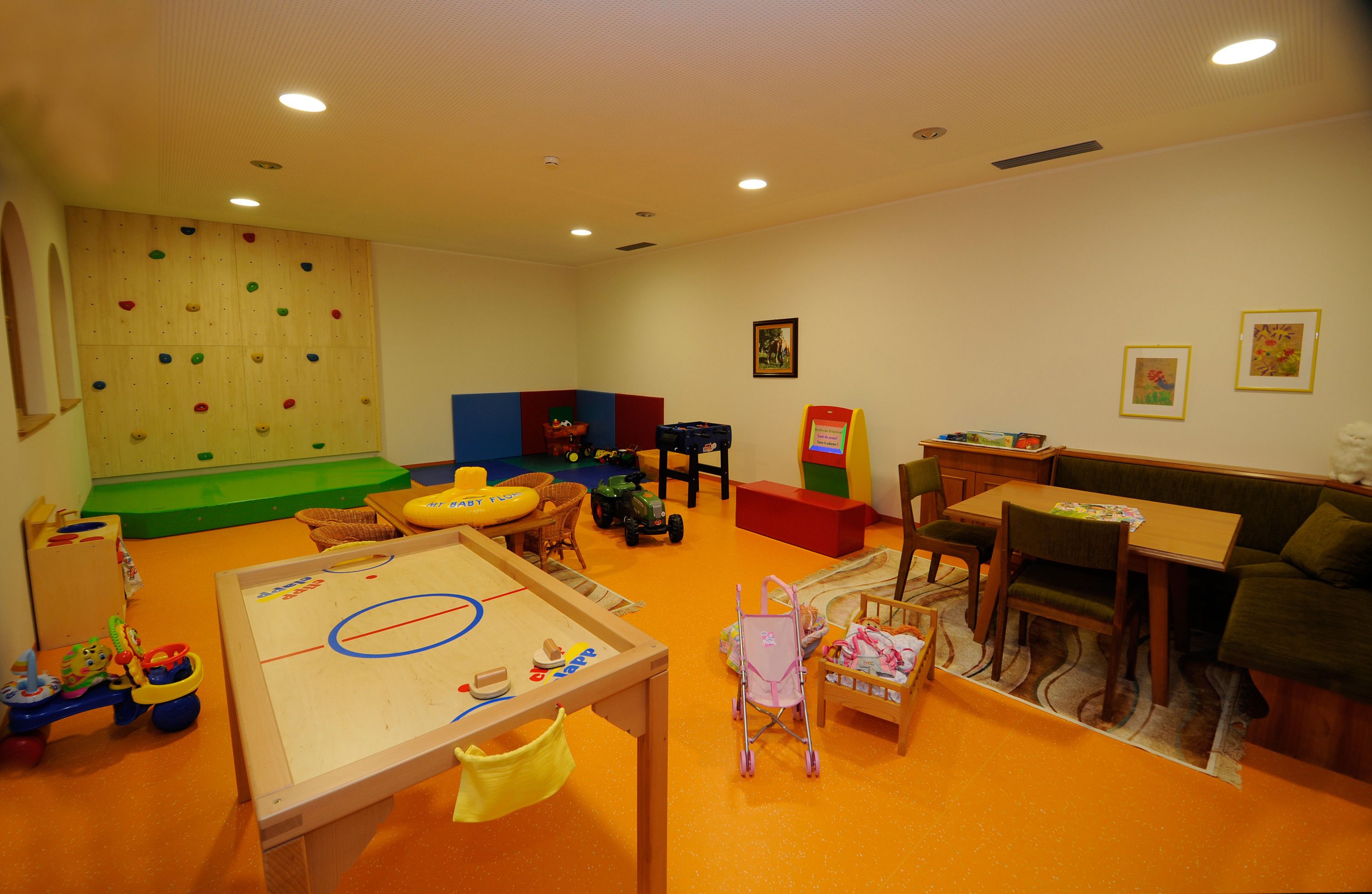 A children's play area with climbing walls, a table with toys, and a sofa.