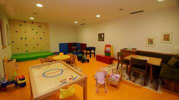 A children's play area with climbing walls, a table with toys, and a sofa.