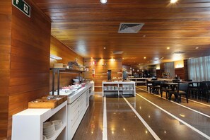 Eine Hotelhalle mit Buffetbereich, Sitzgelegenheiten und einer Rezeption.