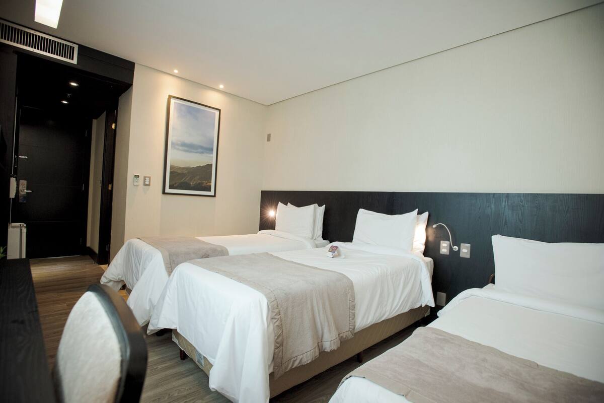 Una habitación de hotel con dos camas, un cuadro grande en la pared y suelo de madera.