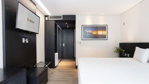 A modern hotel room with a large bed, a TV mounted on the wall, a framed picture, and a plant. - Hotel Park Tower Savassi (Belo Horizonte)