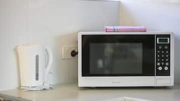 Une cuisine avec un four à micro-ondes blanc, une bouilloire blanche et un évier en acier inoxydable.