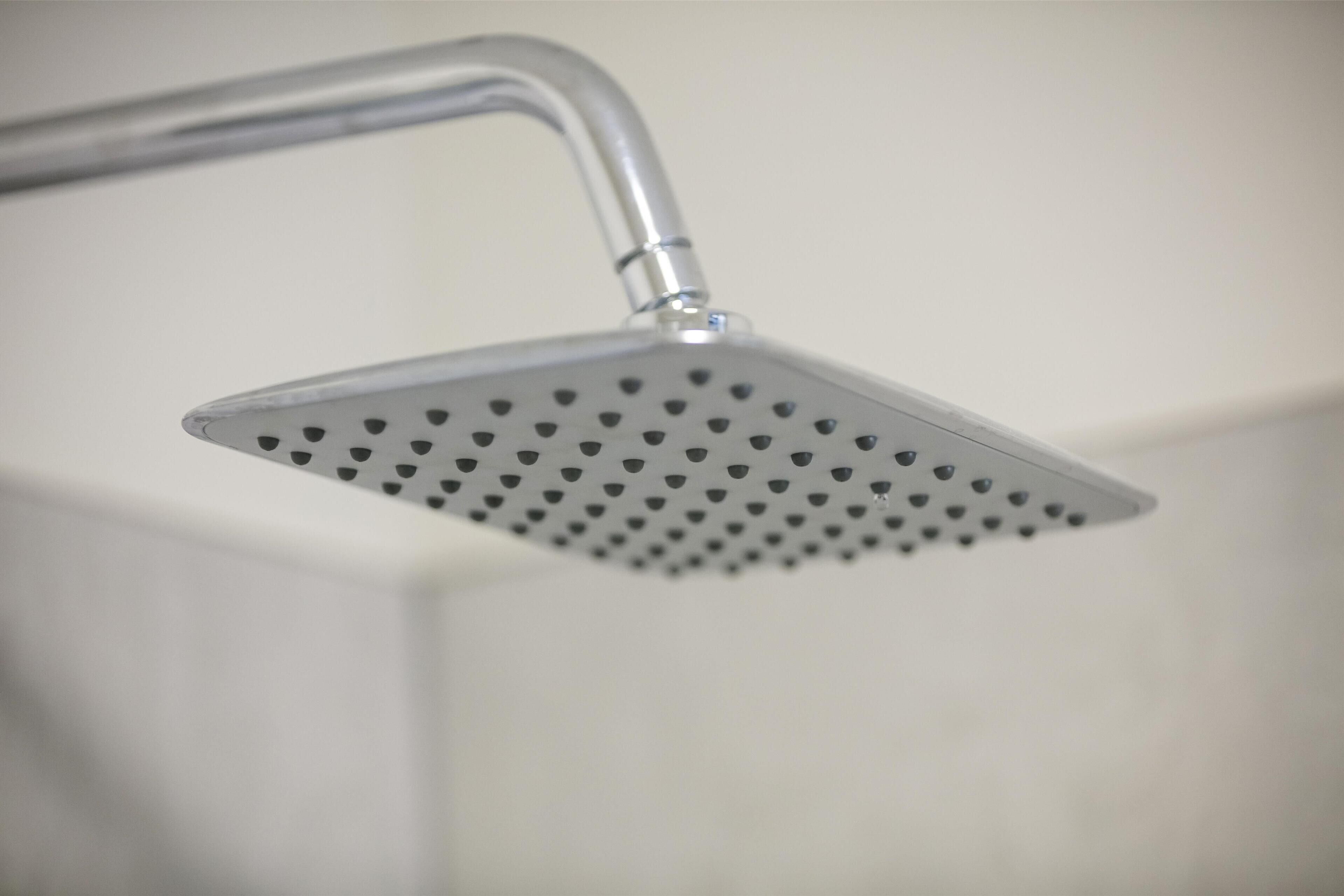 A showerhead with a square design and multiple holes.
