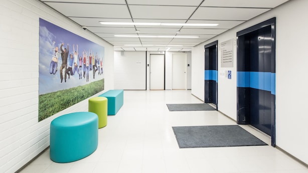 A hallway with a mural, colorful seating, and an elevator. - Forenom Hostel Vantaa Airport (Vantaa)