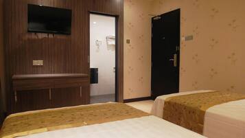 A hotel room with two beds, a TV mounted on the wall, a door, and a shower area.