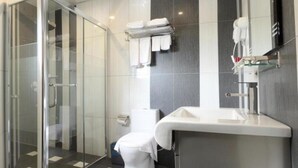 A modern bathroom with a glass shower enclosure, a toilet, and a sink with a towel rack above. - Mandarin Hotel (Kota Kinabalu)