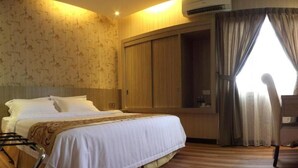 A hotel room with a bed, wooden wardrobe, and an air conditioning unit. - Mandarin Hotel (Kota Kinabalu)