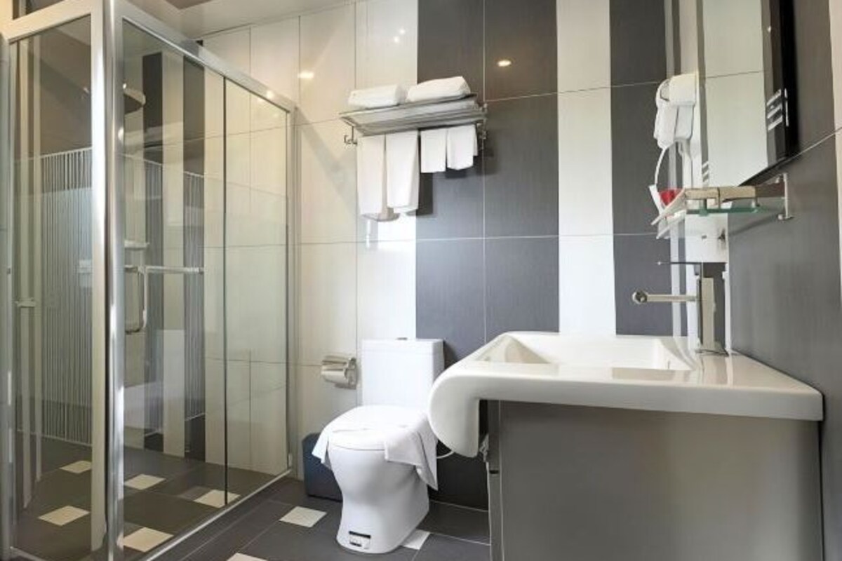 A modern bathroom with a glass shower enclosure, a white toilet, and a sink with a mirror above it.