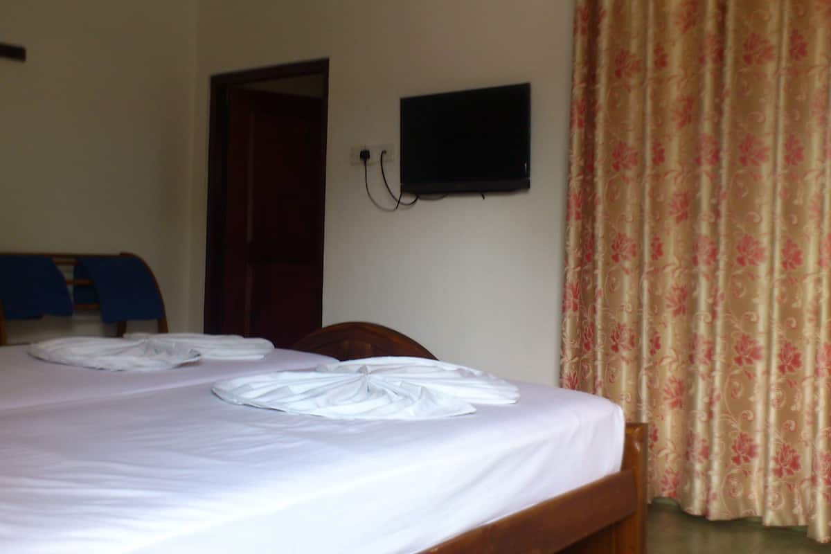 A hotel room with a bed, a chair, a television, and a door.