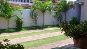 A well-maintained garden with palm trees, a paved walkway, and a white wall. - Ocean View Guesthouse (Negombo)