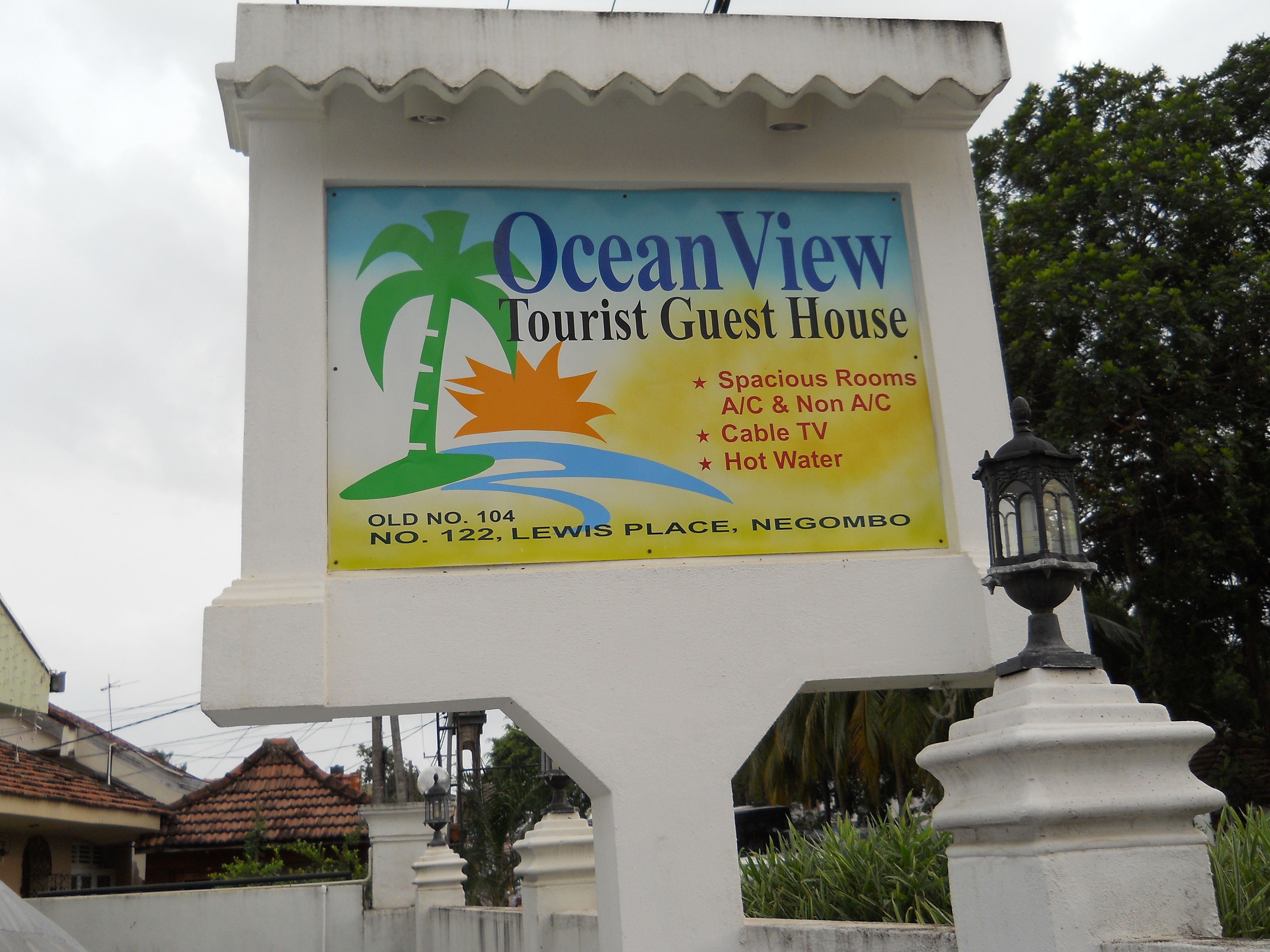 Letrero de Ocean View Tourist Guest House, que enumera servicios como habitaciones amplias, televisión por cable y agua caliente.