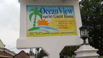 Letrero de Ocean View Tourist Guest House, que enumera servicios como habitaciones amplias, televisión por cable y agua caliente.