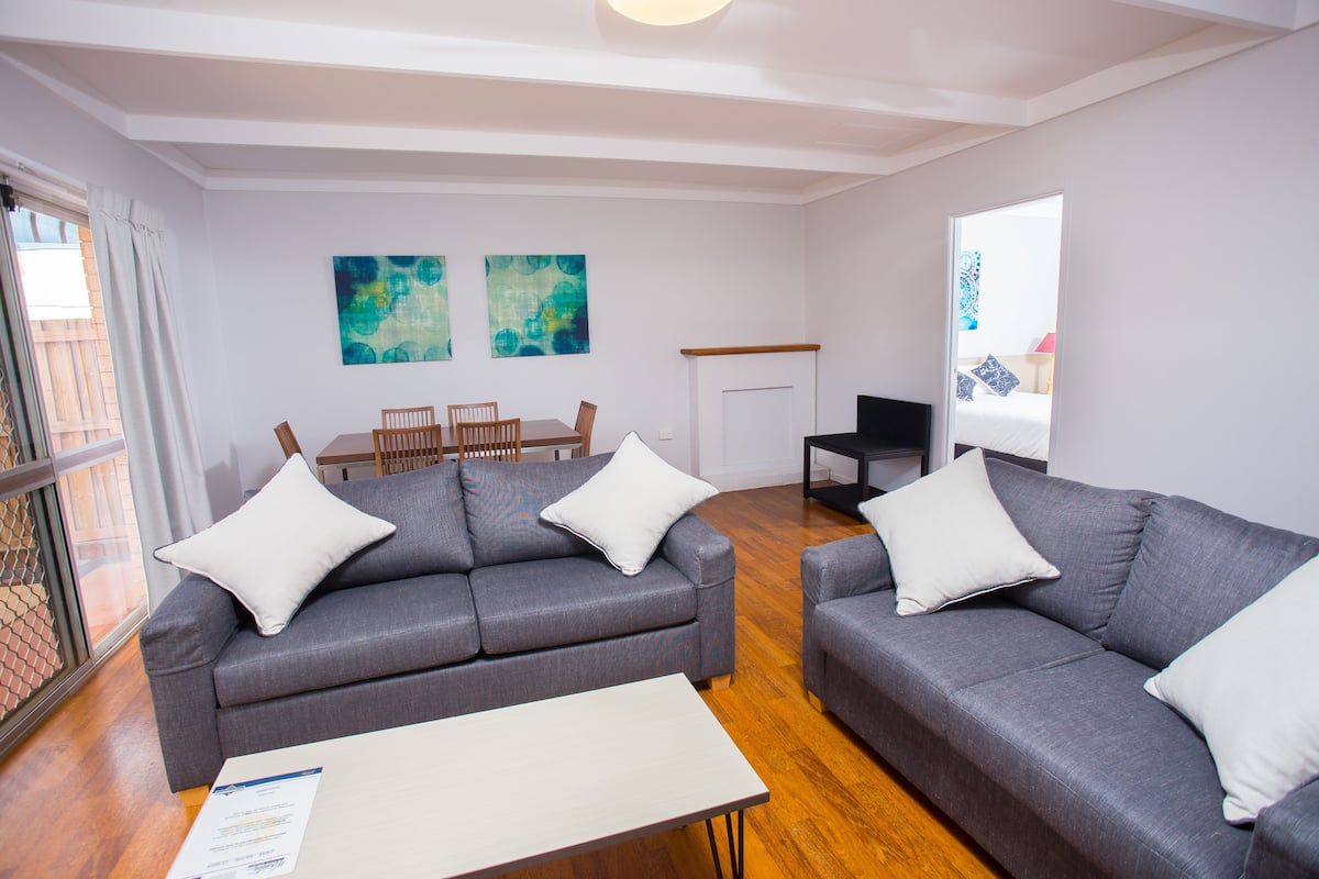 A modern living room with two grey sofas, a wooden coffee table, and a fireplace.
