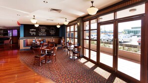 A restaurant with wooden flooring, large windows, and a menu board advertising premium steaks. - Wilsonton Hotel (Wilsonton)