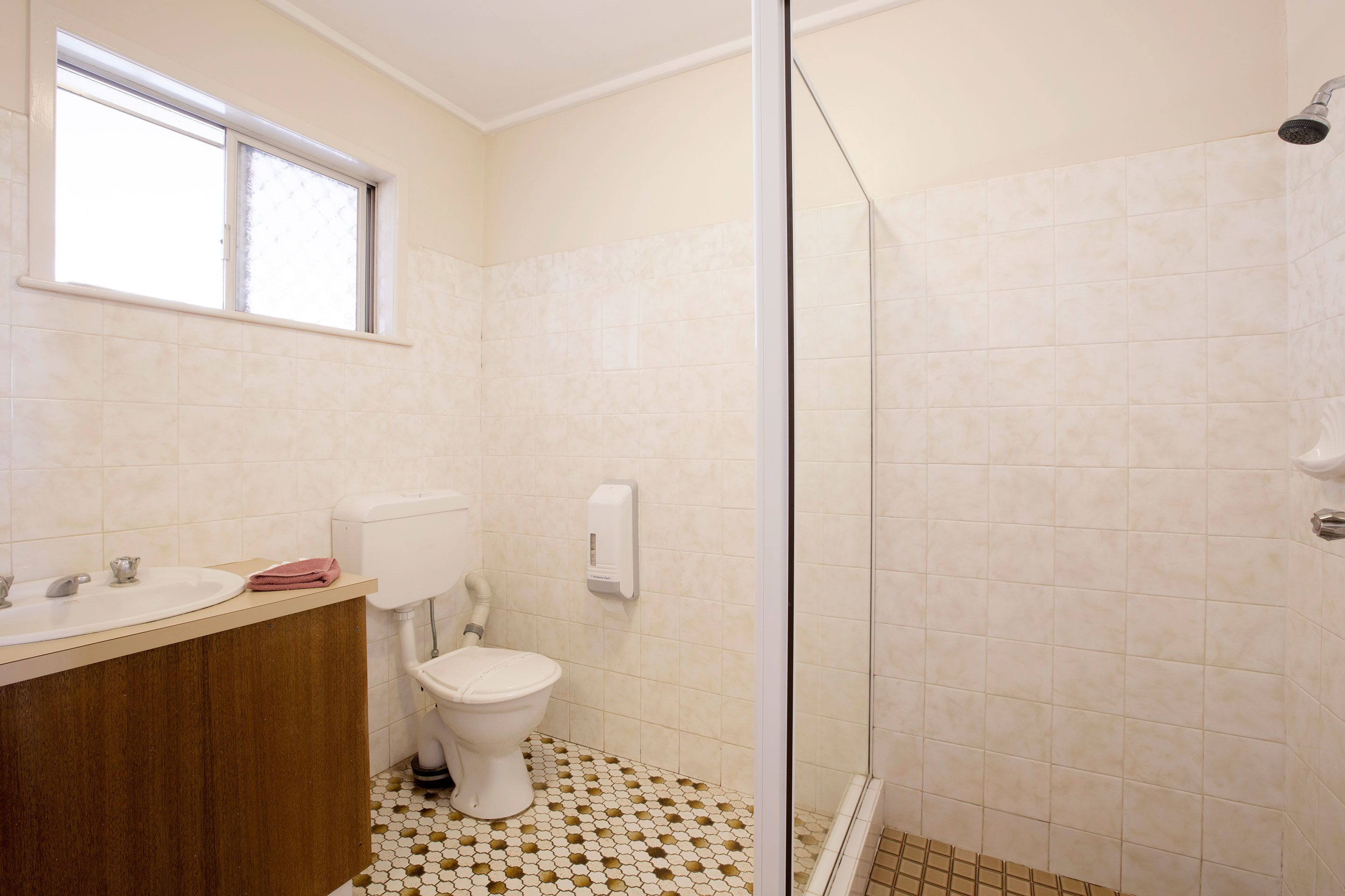 A bathroom with a sink, toilet, and shower area.