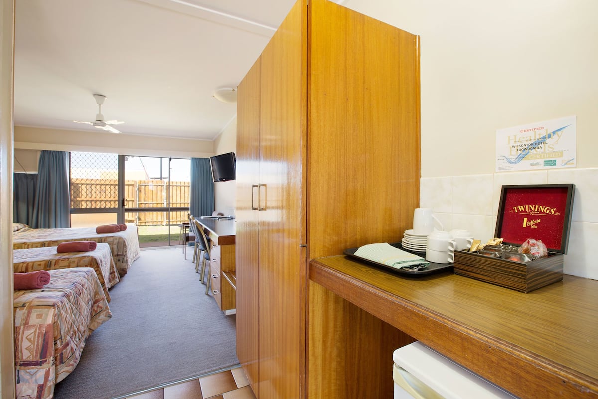 A hotel room with a kitchenette, a dining area, and a balcony.