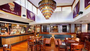 A bar area with wooden flooring, multiple seating arrangements, and a central chandelier. - Wilsonton Hotel (Wilsonton)