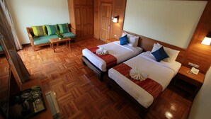 Hotelkamer met twee bedden, een bank, een houten vloer, een kleine tafel en een nachtkastje met telefoon.