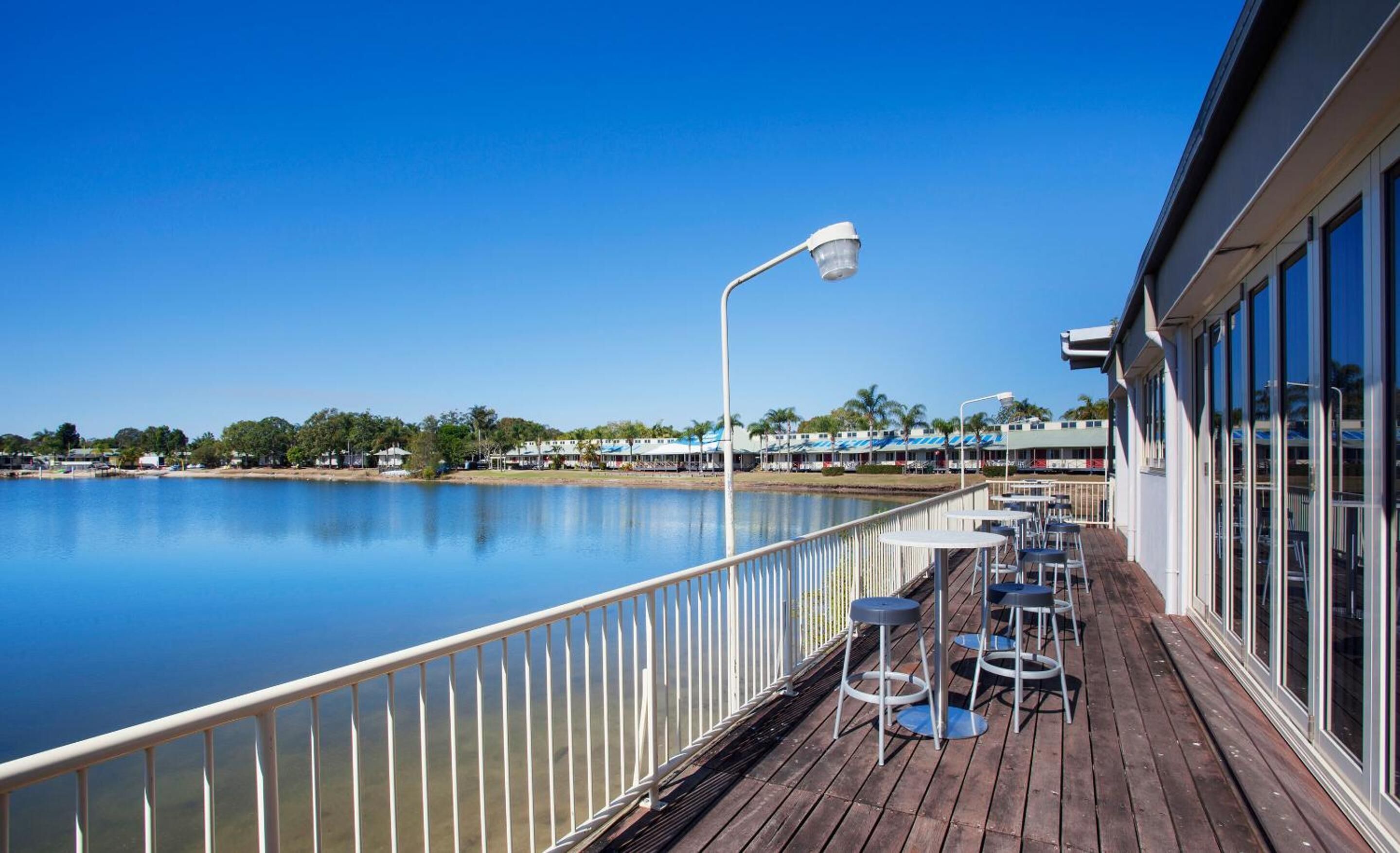 A wooden deck with outdoor seating and a view of a calm lake.