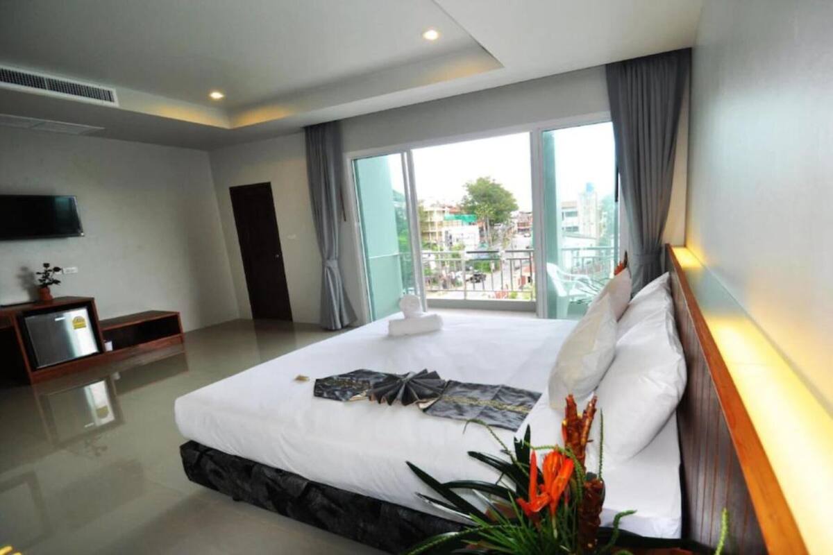 Ein modernes Hotelzimmer mit einem großen Bett, einem Flachbildfernseher und einem Balkon mit Blick auf die Stadt.