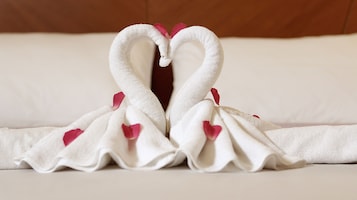 Una toalla dispuesta en forma de dos cisnes con corazones y pétalos de rosa.