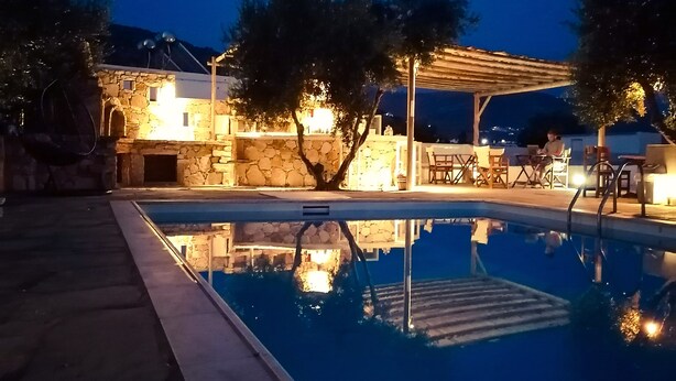 A swimming pool with a stone wall and a pergola. - Diamantis Studios (Naxos)