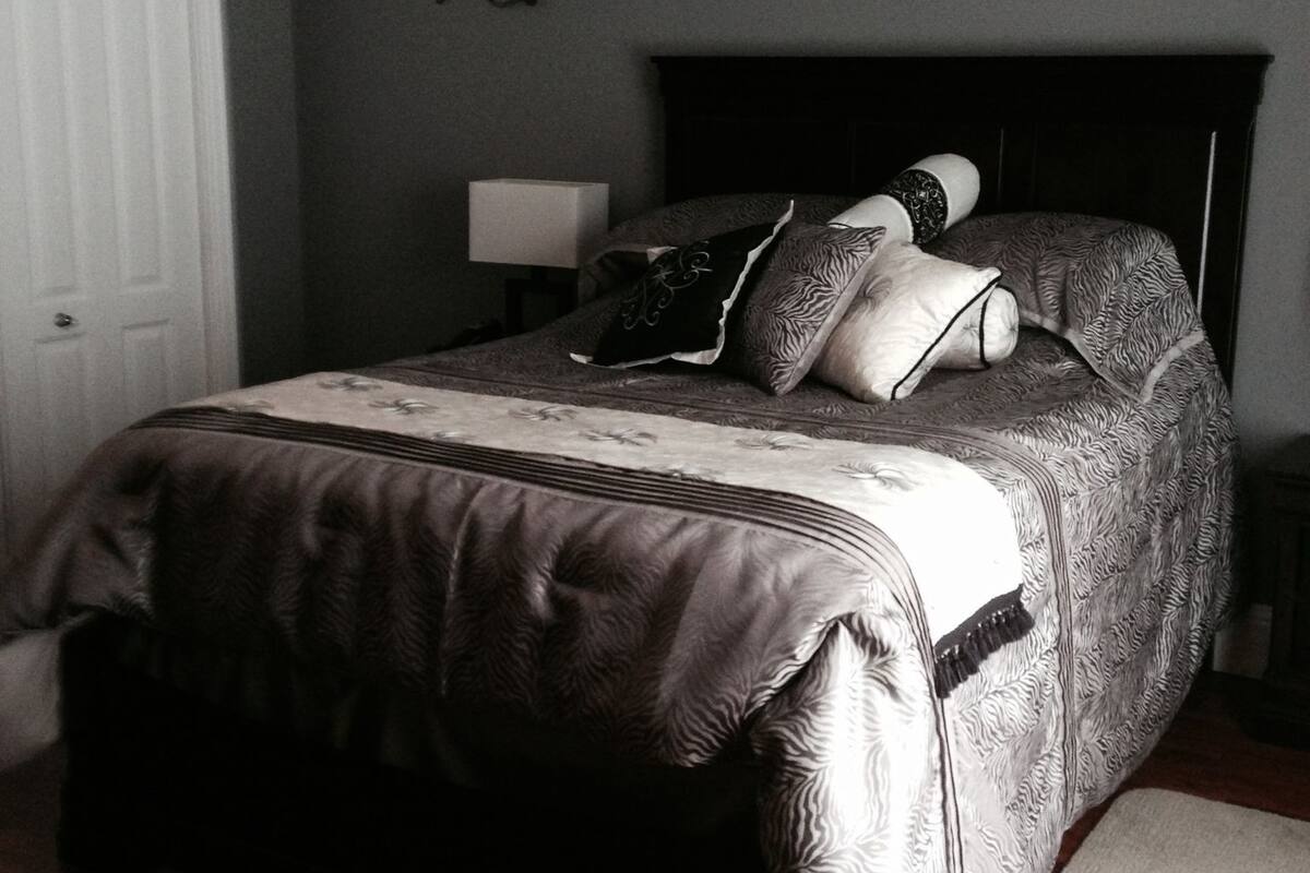 A bedroom with a bed, a nightstand, a lamp, and a door.