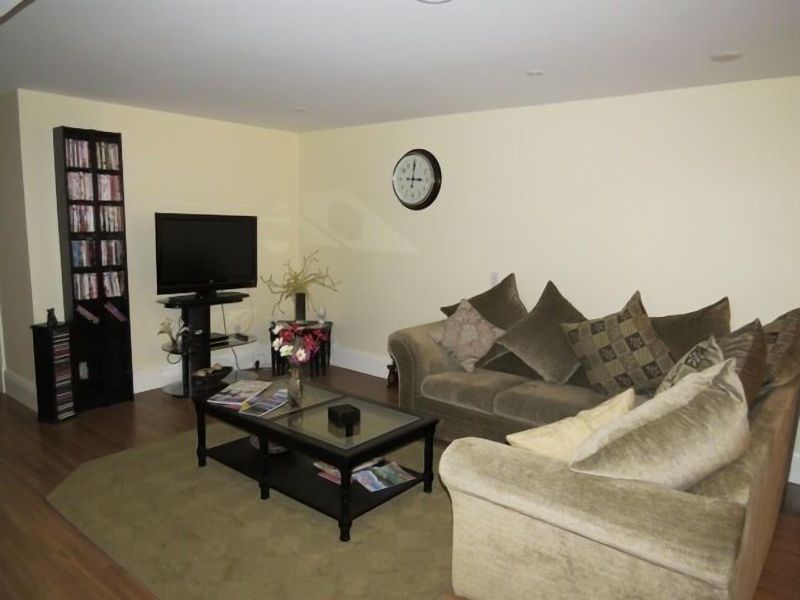A living room with a sofa, a coffee table, a bookshelf, and a television.