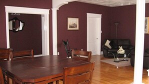 A dining area with a wooden table and chairs, a black leather sofa, and a framed picture on the wall. - Driftwood Heights Bed & Breakfast (Summerside)