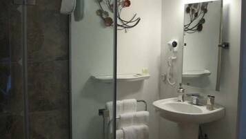 A bathroom with a glass shower enclosure, a sink, and a mirror.