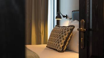 A hotel room with a bed, a patterned pillow, a bedside lamp, and a door.