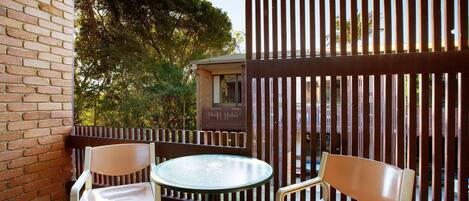 A balcony with two chairs and a table, a brick wall, and a wooden fence.