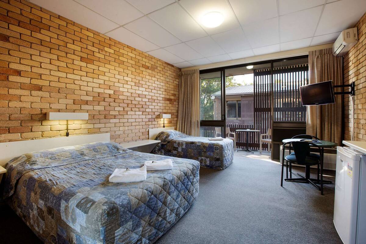Een hotelkamer met twee bedden, een bureau, een stoel en een televisie.