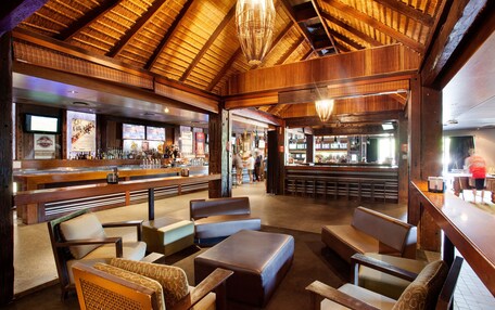 A rustic interior with wooden beams, a bar area, and seating arrangements.
