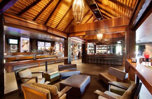 Un interior rústico con vigas de madera, una zona de bar y diferentes disposiciones de asientos.