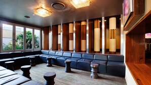 Un espace de détente moderne avec un canapé bleu, des colonnes en bois et un tapis à motifs.