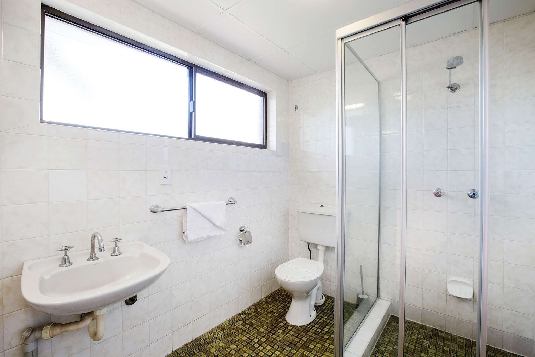 A bathroom with a white sink, toilet, and shower.